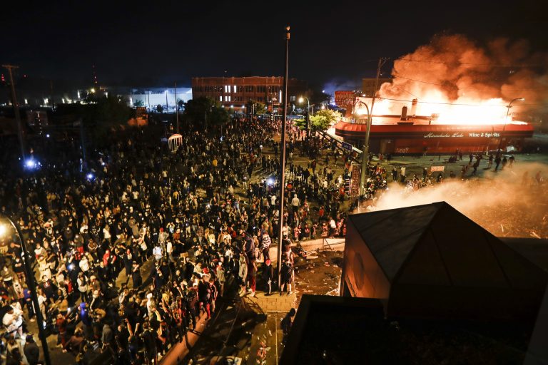 Eine Polizeiwache (rechts unten) und ein Schnapsladen gehen in Minneapolis während der Unruhen in Flammen auf Foto: picture alliance / AP Photo