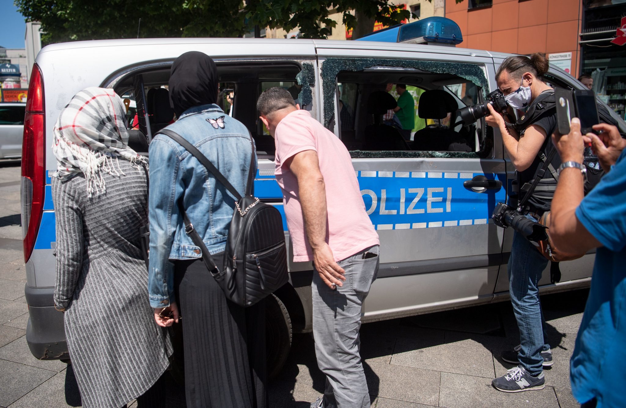 Passanten und Journalisten betrachten einen zerstörten Polizeiwagen nach den Stuttgarter Ausschreitungen Foto: picture alliance/Marijan Murat/dpa