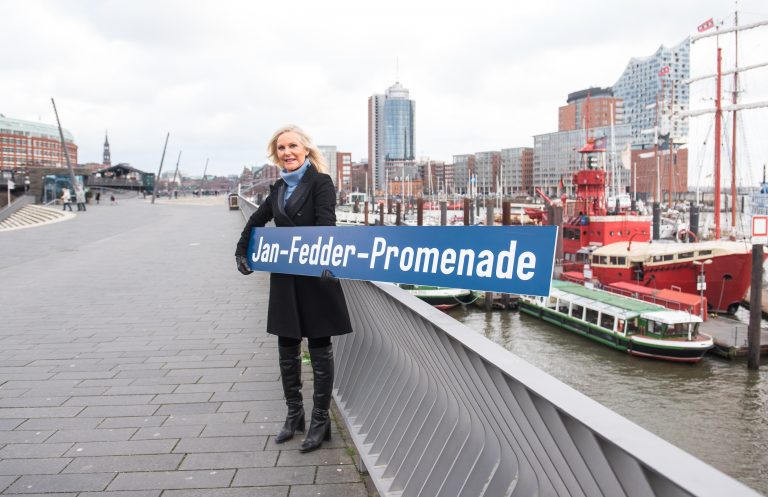 Die Witwe des Schauspielers Jan Fedder, Marion Fedder, hält eines der neuen Promenadenschilder Foto: picture alliance/dpa | Daniel Bockwoldt