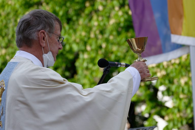 Pfarrer Ulrich Hinzen am Sonntag vor einer Regenbogenfahne bei einem Open-Air-Gottesdienst in Köln