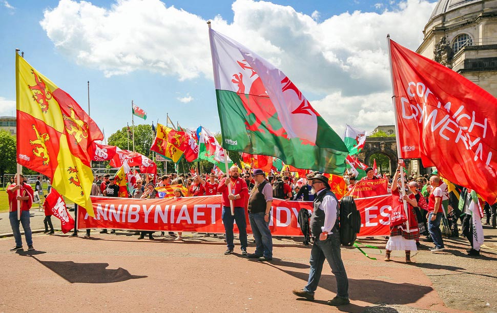"Unabhängigkeitsmarsch" von Yes Cymru in Cardiff, Mai 2019, mit der walisischen Nationalflagge und dem Löwenbanner des Owen Glendower - Owain Glyndŵr (etwa 1359 - etwa 1415), der als letzter walisischer Führer die Unabhängigkeit von England zu erkämpfen suchte Foto: Wikimedia/ Ifan Morgan Jones (CC BY-SA 4.0) https://bit.ly/3wBuhIO