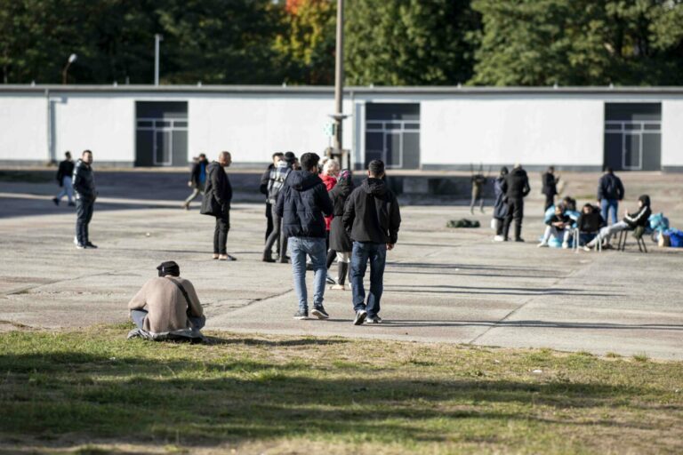 Asylsuchende laufen in der Erstaufnahmeeinrichtung Eisenhüttenstadt über einen Platz. Foto: picture alliance/dpa | Fabian Sommer