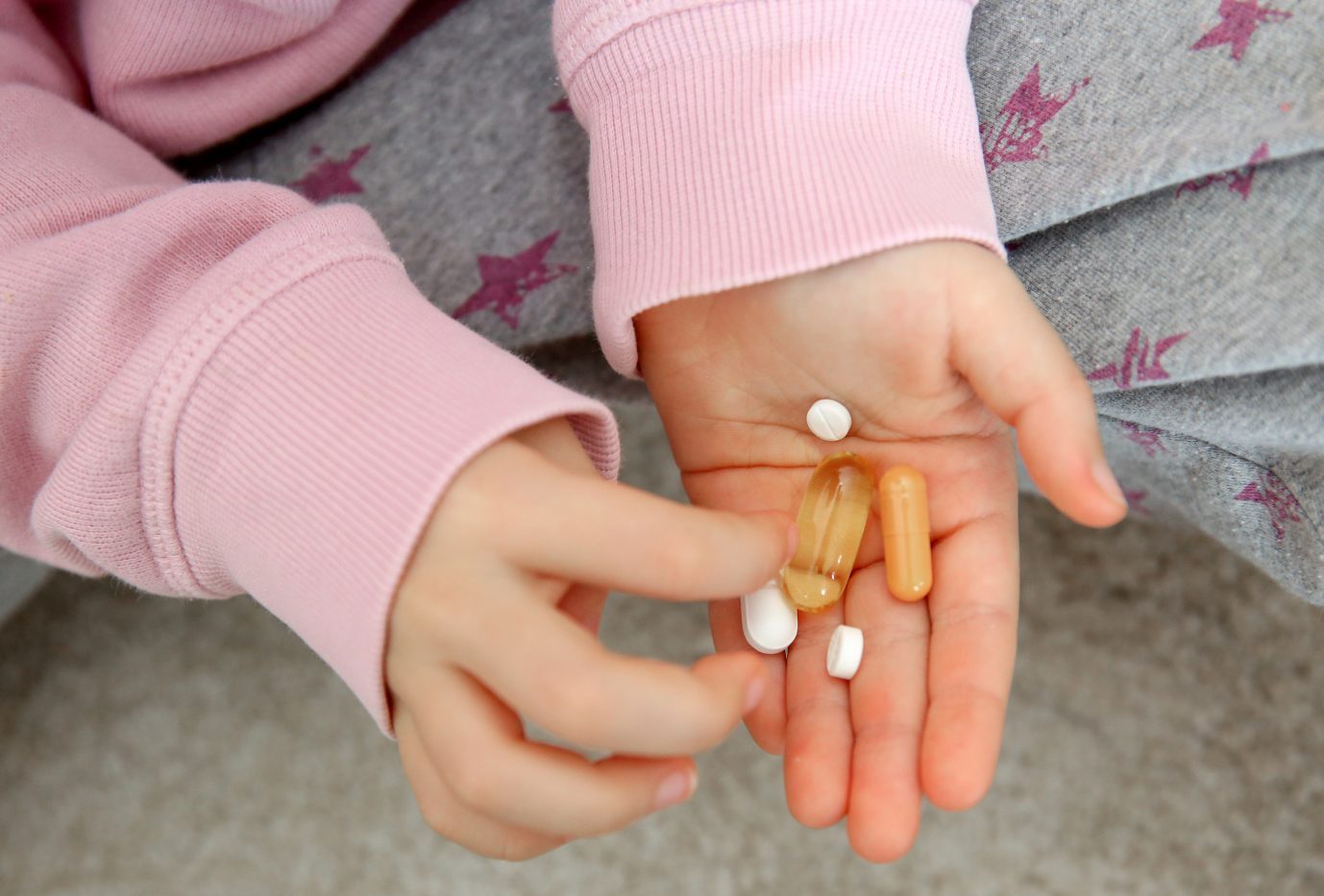 Kind hält Tabletten in der Hand: Texas Gouverneur Greg Abbott will die Behandlung von Minderjährigen mit Pubertätsblockern oder Hormontherapien als Kindesmißbrauch ahnden
