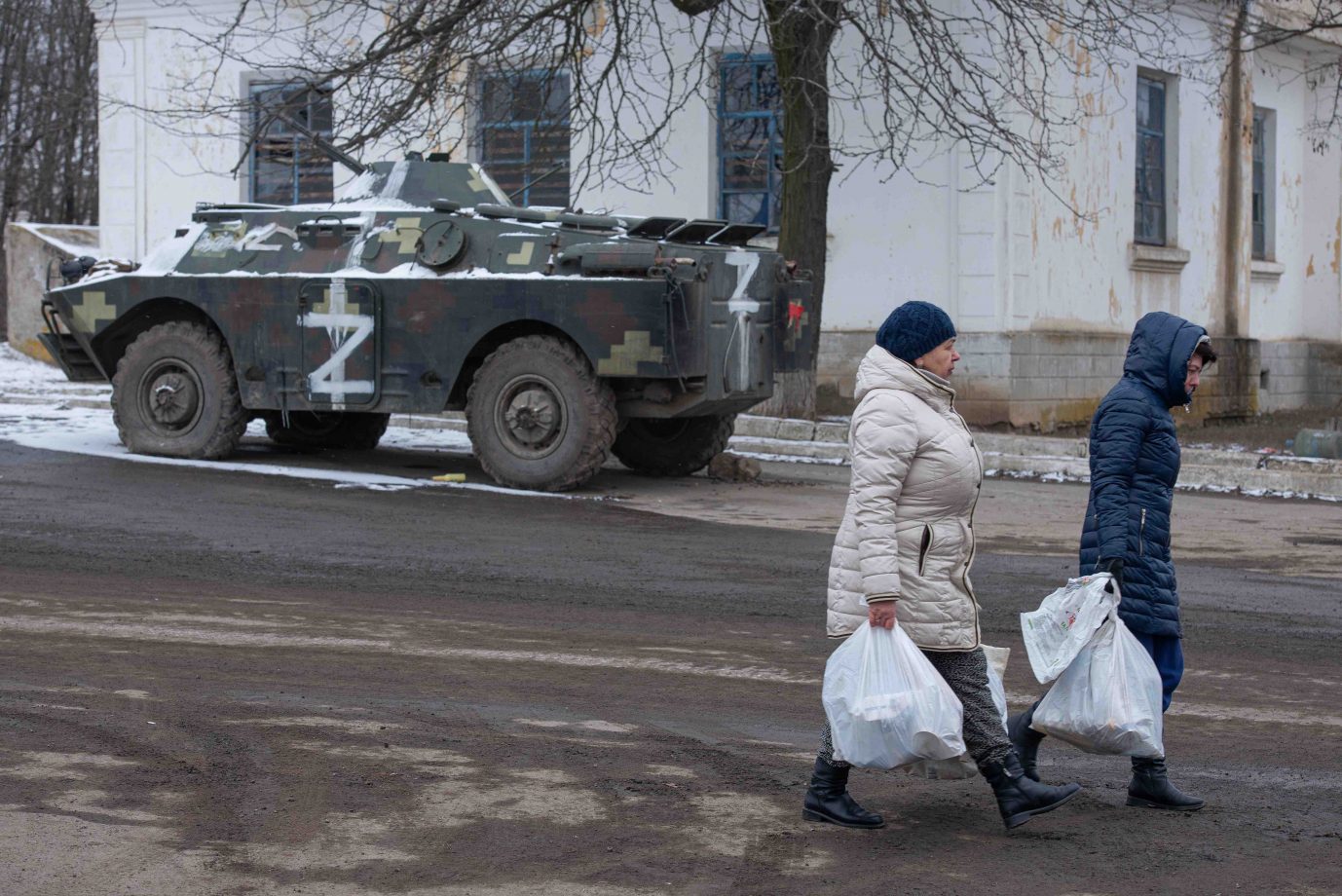 Zivilisten laufen an einem russischen Schützenpanzer vorbei Viele Ukrainer leben mittlerweile unter russischer Besatzung Foto: picture alliance / AA | Stringer