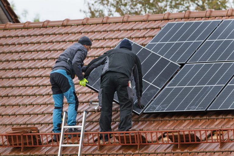 Techniker montieren eine Photovoltaikanlage auf dem Dach eines Wohnhauses