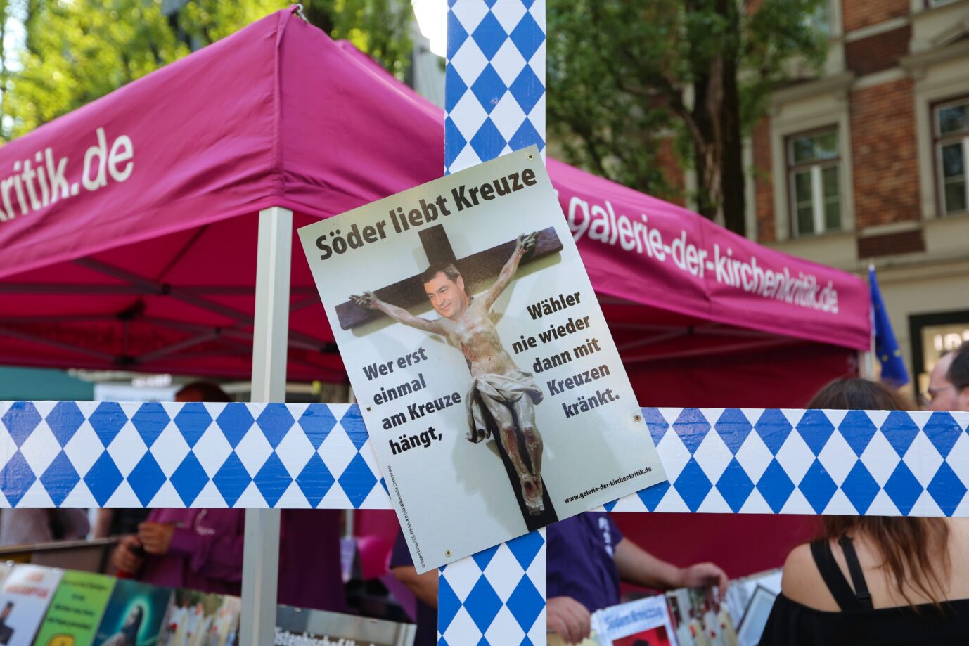 Gegner von dem Kreuzerlaß zeigen ein Spottplakat gegen Bayerns Ministerpräsident Markus Söder (CSU) in München (Archivbild) Foto: picture alliance / NurPhoto | Alexander Pohl