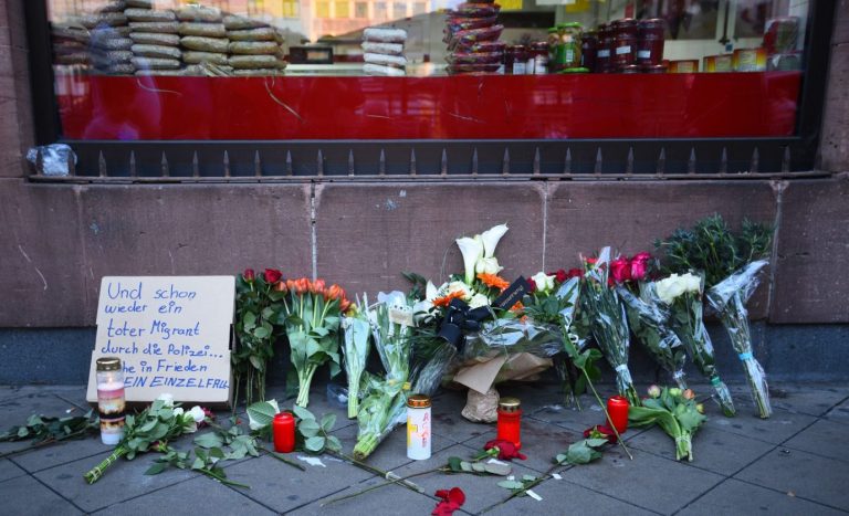 Blumen und Kerzen in Mannheim an der Stelle, an der ein 47jähriger am Montag bei einer Poliziekontrolle zu Tode kam: Auf einem Schild steht „Und schon wieder ein toter Migrant durch die Polizei“