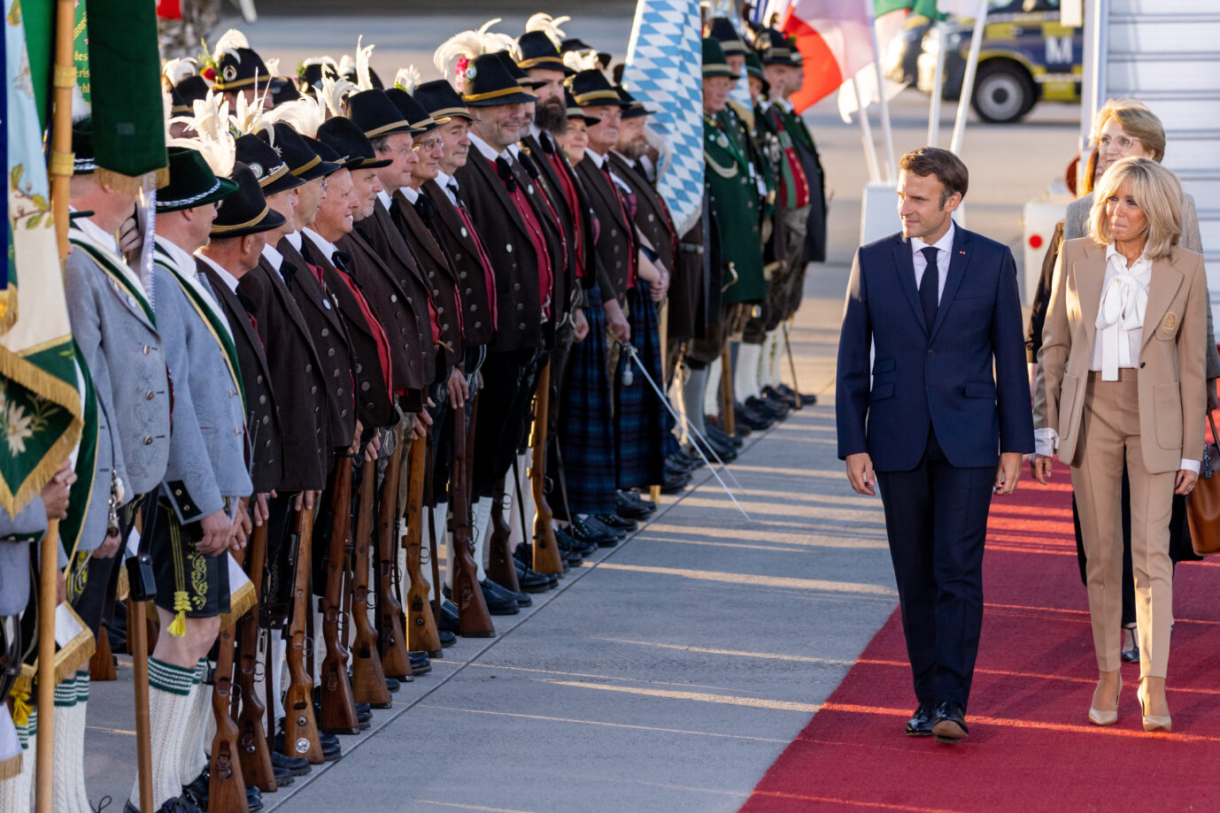 Frankreichs Präsident Emmanuel Macron mit seiner Frau Brigitte bei der Ankunft am Münchner Flughafen: Bayerische Trachtenträger stehen zum Empfang Spalier