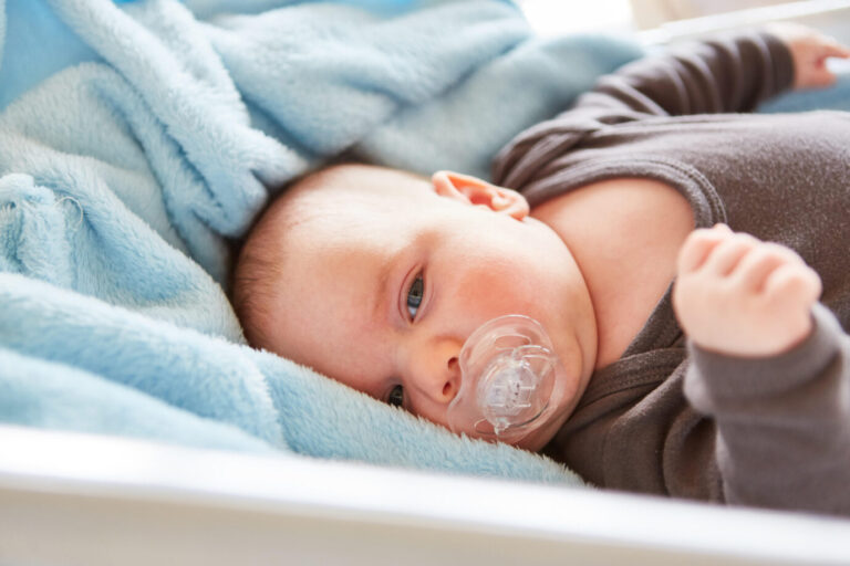 Ein Baby liegt in auf einer hellblauen Decke in einem Babybett: Auch ungeborene Kinder sind lebenswert