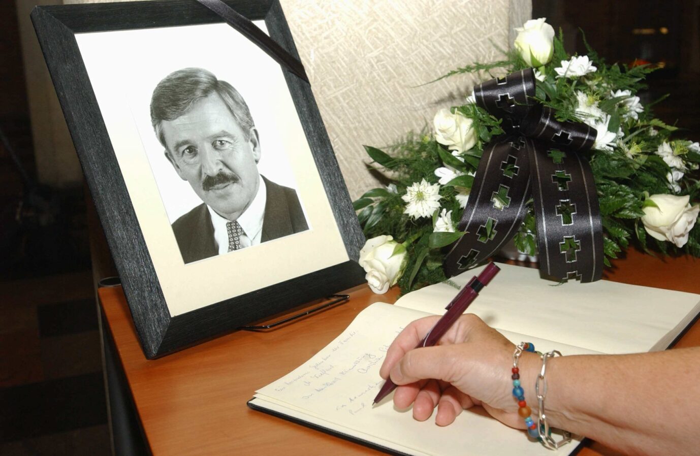 Ein Foto des 2003 verstorbenen FDP-Politikers Jürgen Möllemann, daneben ein Blumenstrauß und ein Kondolenzbuch, wo sich jemand namentlich einträgt.