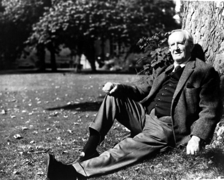 J.R.R. Tolkien, Schöpfer der "Die Ringe der Macht", sitzt gegen einen Baum gelehnt und schaut in die Kamera, das Foto ist schwarz-weiß