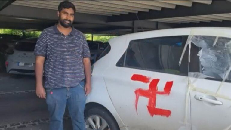 Manoj Subramaniam (Grüne) vor seinem beschädigten und mit einem Hakenkreuz beschmierten Auto. Er hatte auch diese rechte Gewalttat vorgetäuscht.