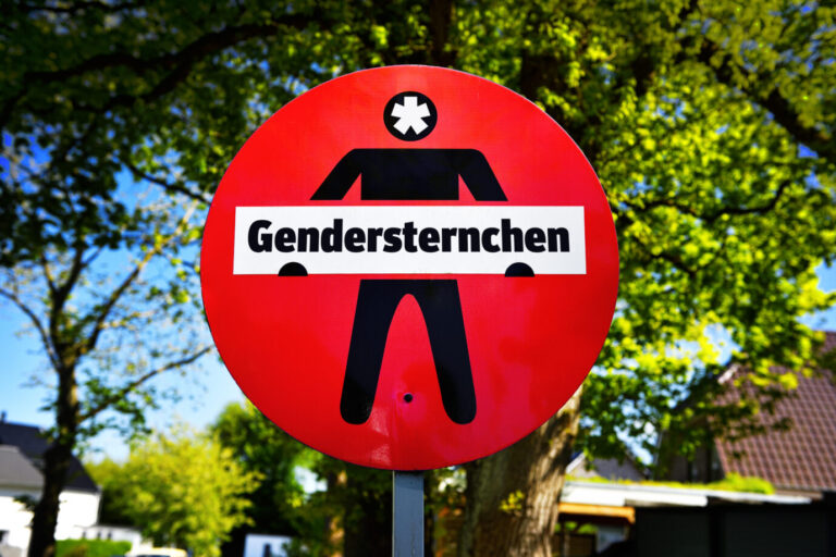 Schild mit der Aufschrift Gendersternchen, Symbolfoto für den Streit um gendergerechte Sprache in Deutschland, im Hintergrund Bäume an einem schönen Tag, Quelle: picture alliance / CHROMORANGE / Christian Ohde
