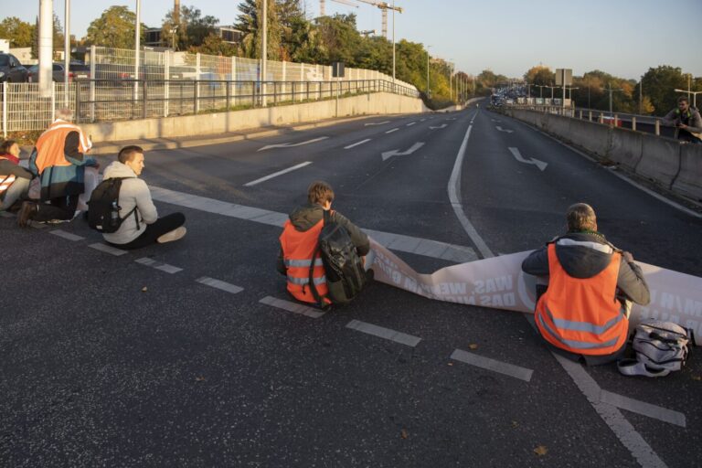 Mitglieder der Umweltschutz-Gruppe "Letzte Generation" blockieren eine Autobahn-Ausfahrt am Spandauer Damm. Auch in Wien gibt es Blockaden.
