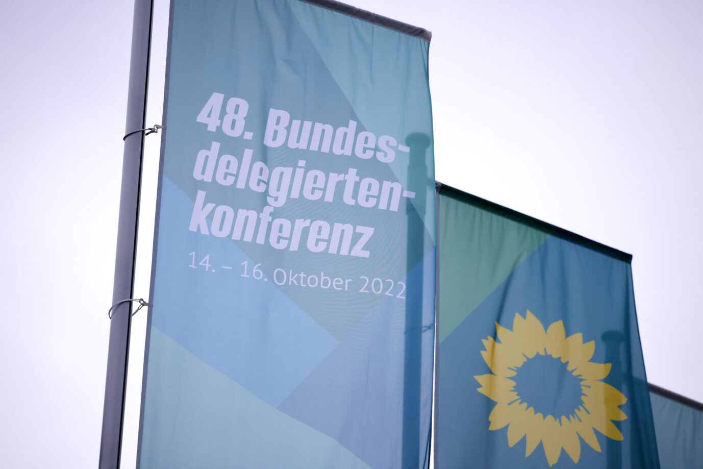 Zwei Flaggen vor grauem Himmel bewerben den Bundesparteitag der Grünen.