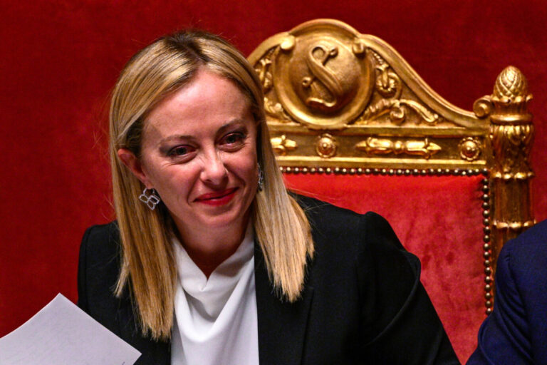 Die italienische Premierministerin Georgia Meloni von der Fratelli d´Italia sitzt auf einem roten Stuhl und lächelt.