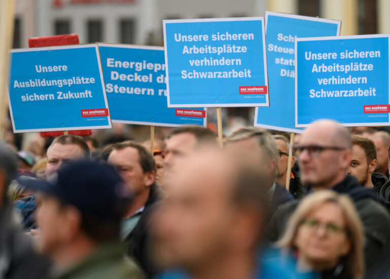 Demonstranten halten auf einer Demo Schilder mit Forderungen aus dem deutschen Handwerk in die Höhe