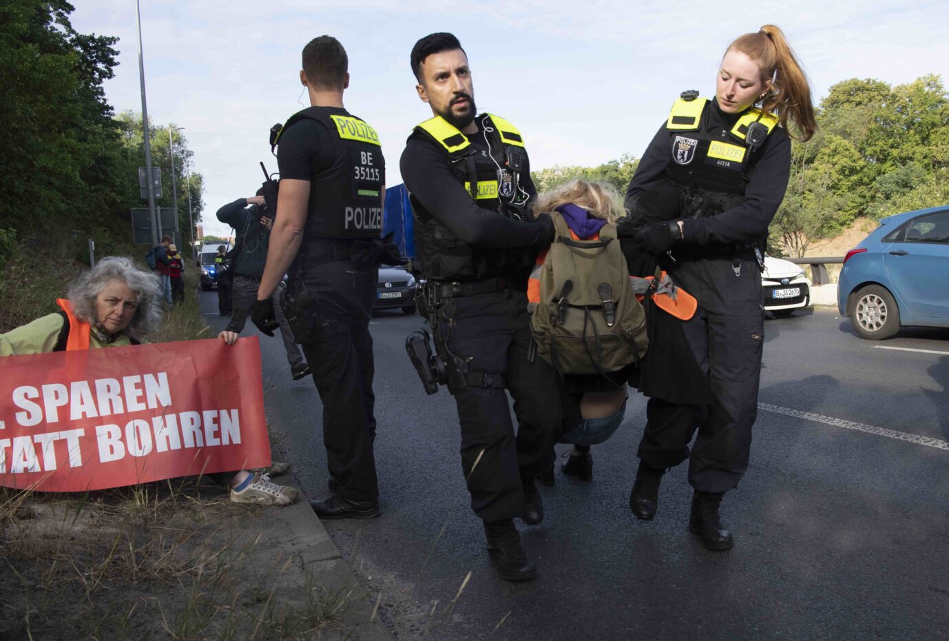 Zwei Polizisten tragen einen Demonstranten der "Letzten Generation" von der Berliner Stadtautobahn