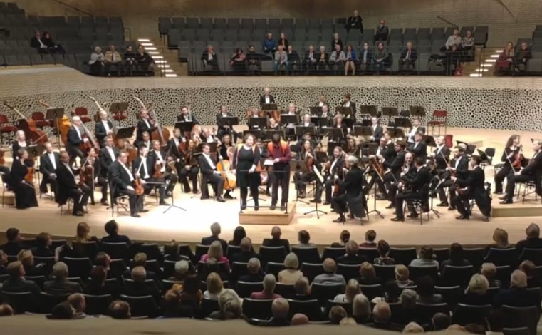Die Störer der "Letzten Generation", als sie sich am Dirigentenpult der Elbphilharmonie festkleben.