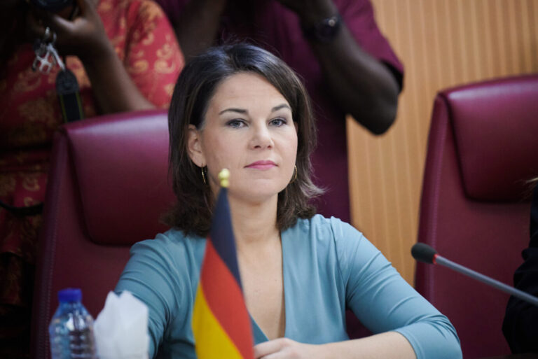 Außenministerin Annalena Baerbock sitzt vor einer Deutschlandfahne.