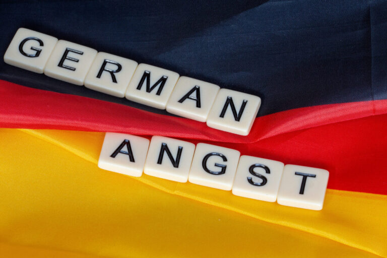 Scrabble-Steine vor einer Deutschlandflagge formen die Worte "German Angst".