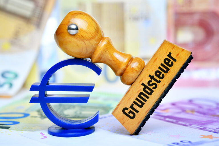 Ein Stempel mit der Aufschrift „Grundsteuer“ ist an ein Eurozeichen gelehnt.