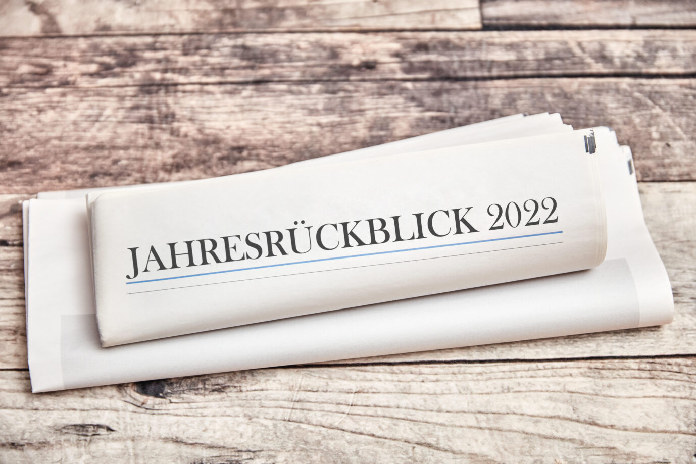 Auf einer Zeitung, die auf einem Holztisch liegt, steht „Jahresrückblick 2022“ geschrieben.