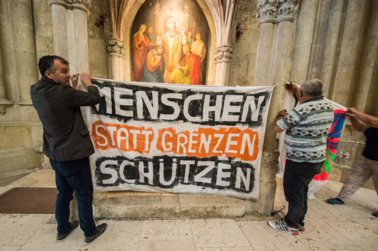 Flüchtlinge hängen am 06.07.2016 im Dom St. Peter in Regensburg (Bayern) ein Transparent mit der Aufschrift "Menschen statt Grenzen schützen" auf. Die Gruppe demonstriert seit Dienstag für ein Bleiberecht und gegen die Einstufung einiger Balkan-Staaten als sichere Herkunftsländer. Zudem baten die 45 Demonstranten um Kirchenasyl. Foto: Armin Weigel/dpa ++