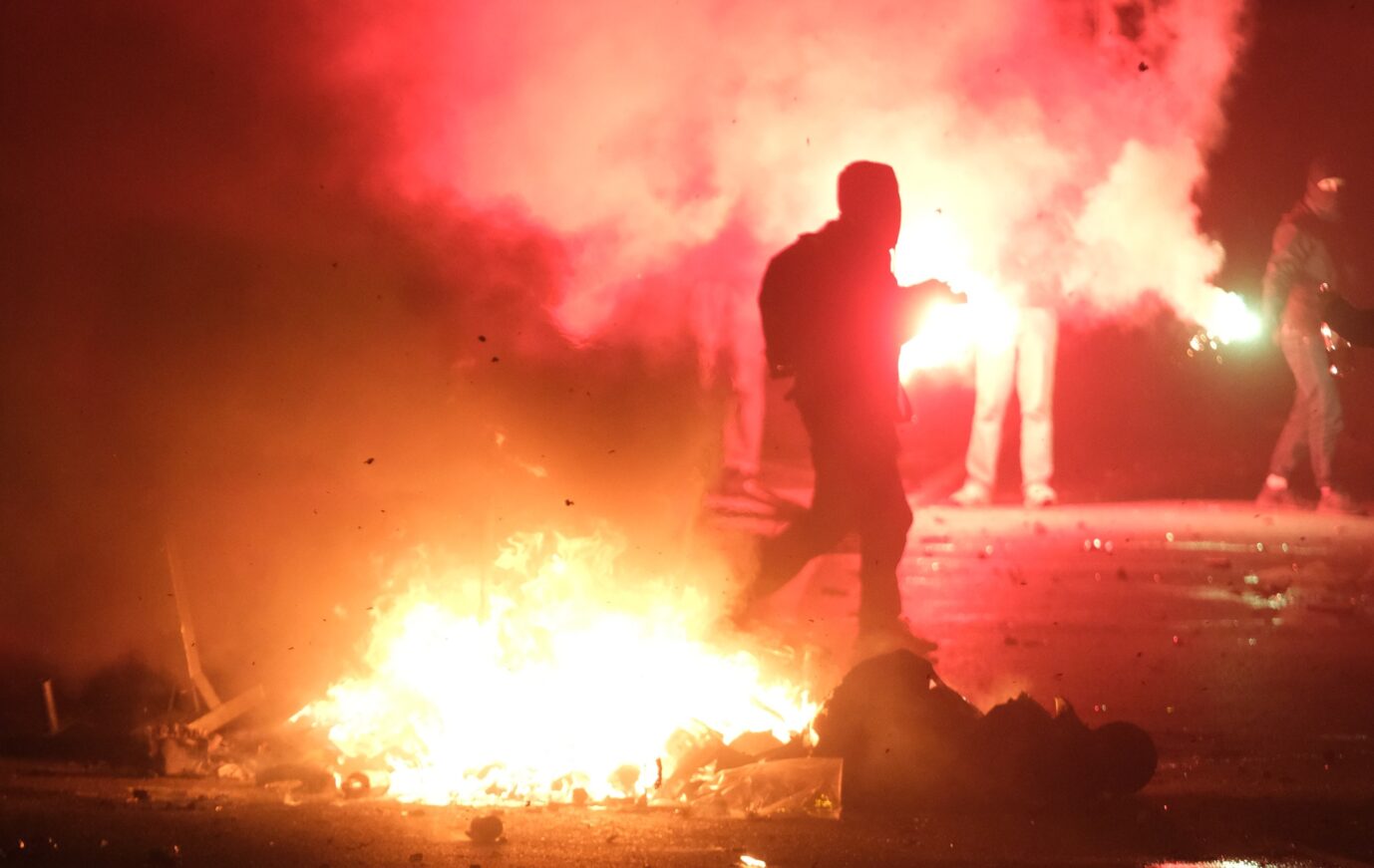 Silvester in Leipzig: Eine Person geht an einer brennenden Barrikade vorbei.