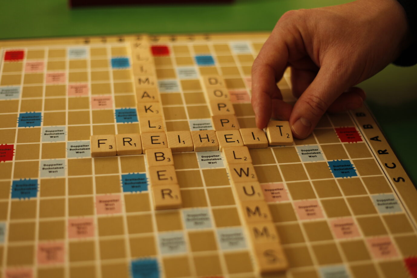 Ein Scrabble-Spielfeld zeigt die Begriffe "Doppelwums", "Freiheit" und "Klimakleber".