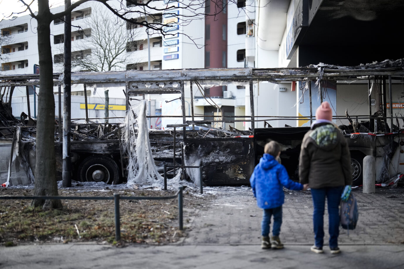Eine Mutter und ihr Kind blicken nach der Silvesternacht in Berlin auf einen abgebrannten Bus: Krawalle junger Männer läuteten das neue Jahr ein