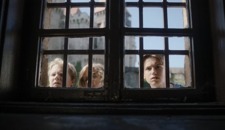 Die Nachwuchsdetektive der "Drei ???" schauen durch ein vergittertes Fenster.