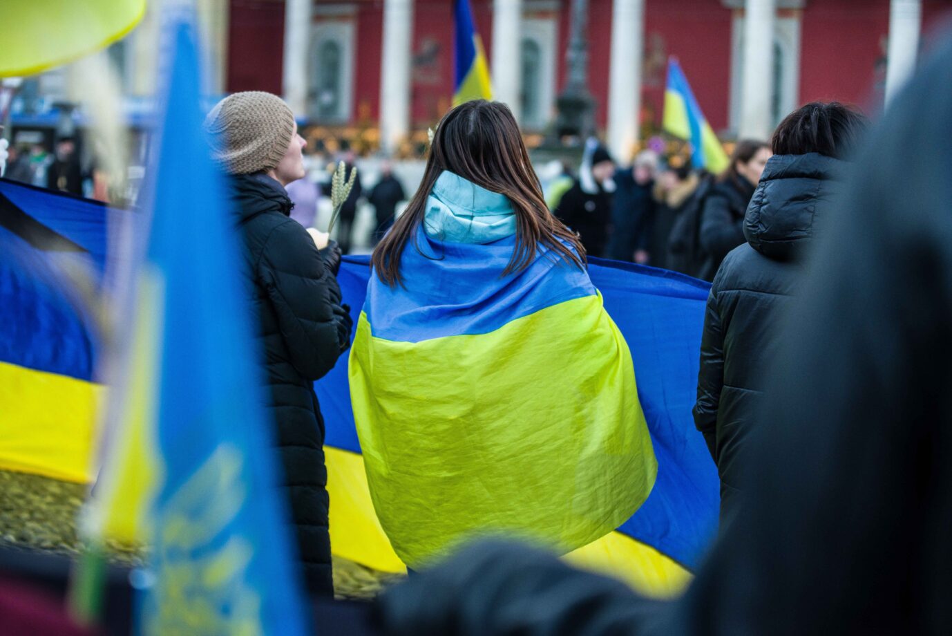 Eine Frau ist während einer Demonstration in die Flagge der Ukraine gehüllt.