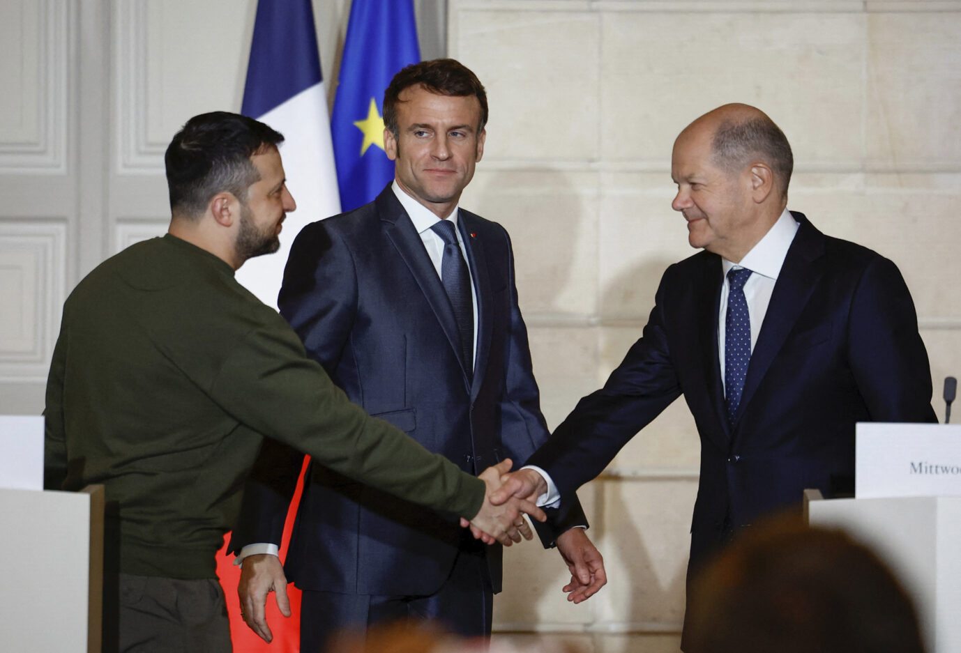 Kanzler Olaf Scholz reicht dem Präsidenten der Ukaine, Wolodymyr Selenskyj die Hand. Frankreichs Präsident Emmanuel Macron schaut zu.