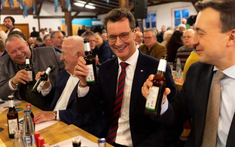 Nordrhein-Westfalens Landesvater Hendrik Wüst (CDU) (2. v. r.) prostet mit einer Flasche Bier zu.