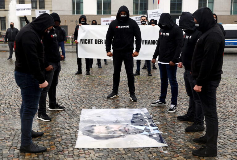 Das Bild zeigt Mitglieder der Gruppe „Muslim Interaktiv“, die in Berlin vor der Französischen Botschaft ein Foto des Französischen Präsidenten Emmanuel Macron auf den Boden gelegt haben.