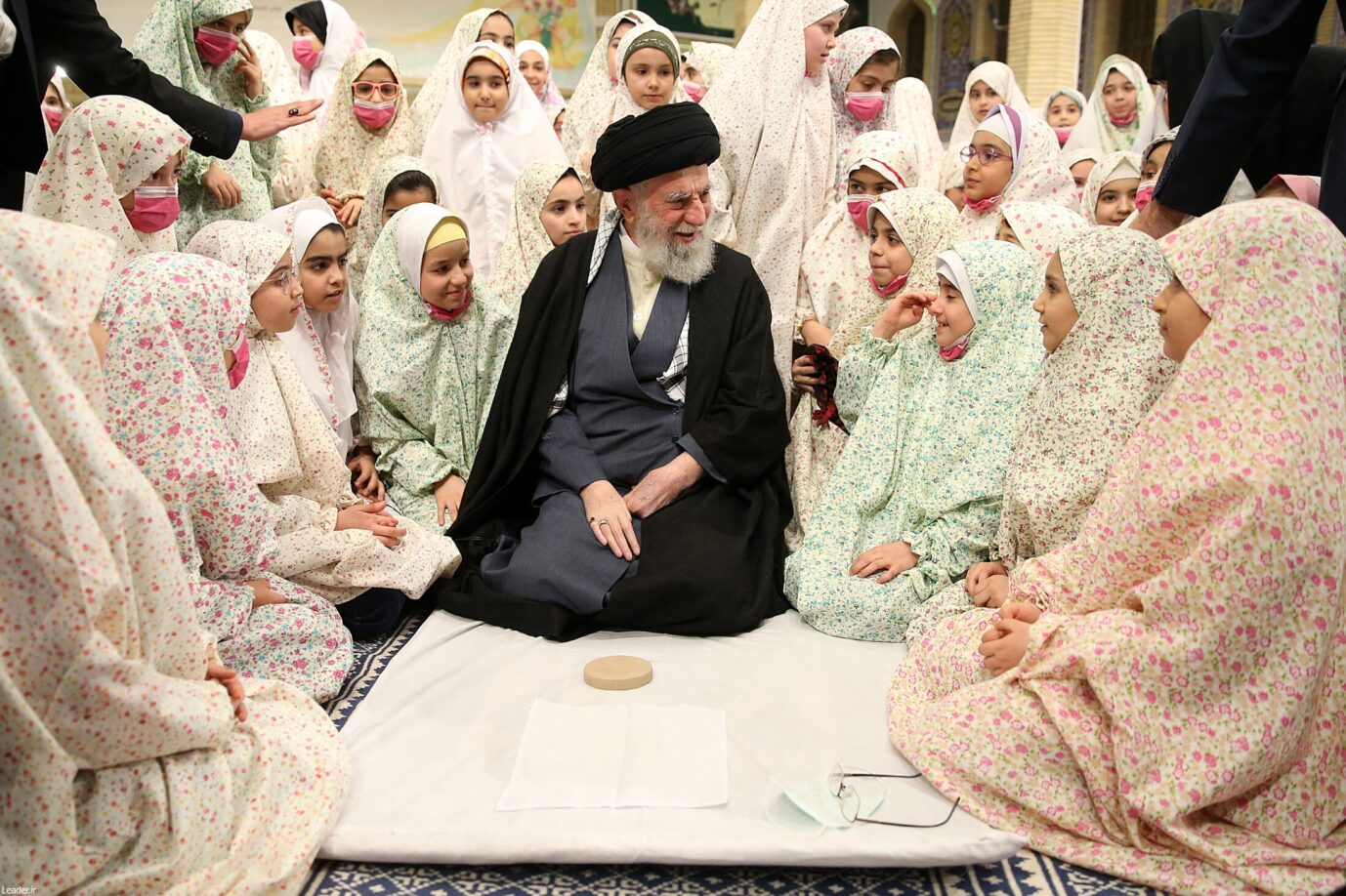 Der iranische Ayatollah Ali Khamenei läßt sich mit einer Gruppe Mädchen ablichten – hat die iranische Regierung es aus Rache auf die Kinder abgesehen?