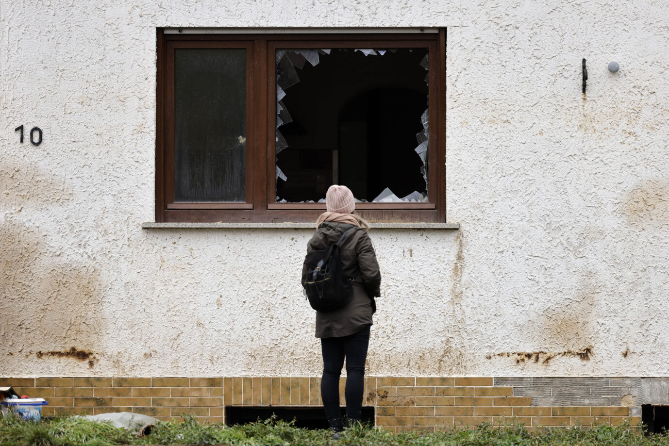 Eine Frau blick auf ein Haus, das von der Flut im Ahrtal beschädigt wurde: Es ist noch lange nicht wieder alles beim Alten