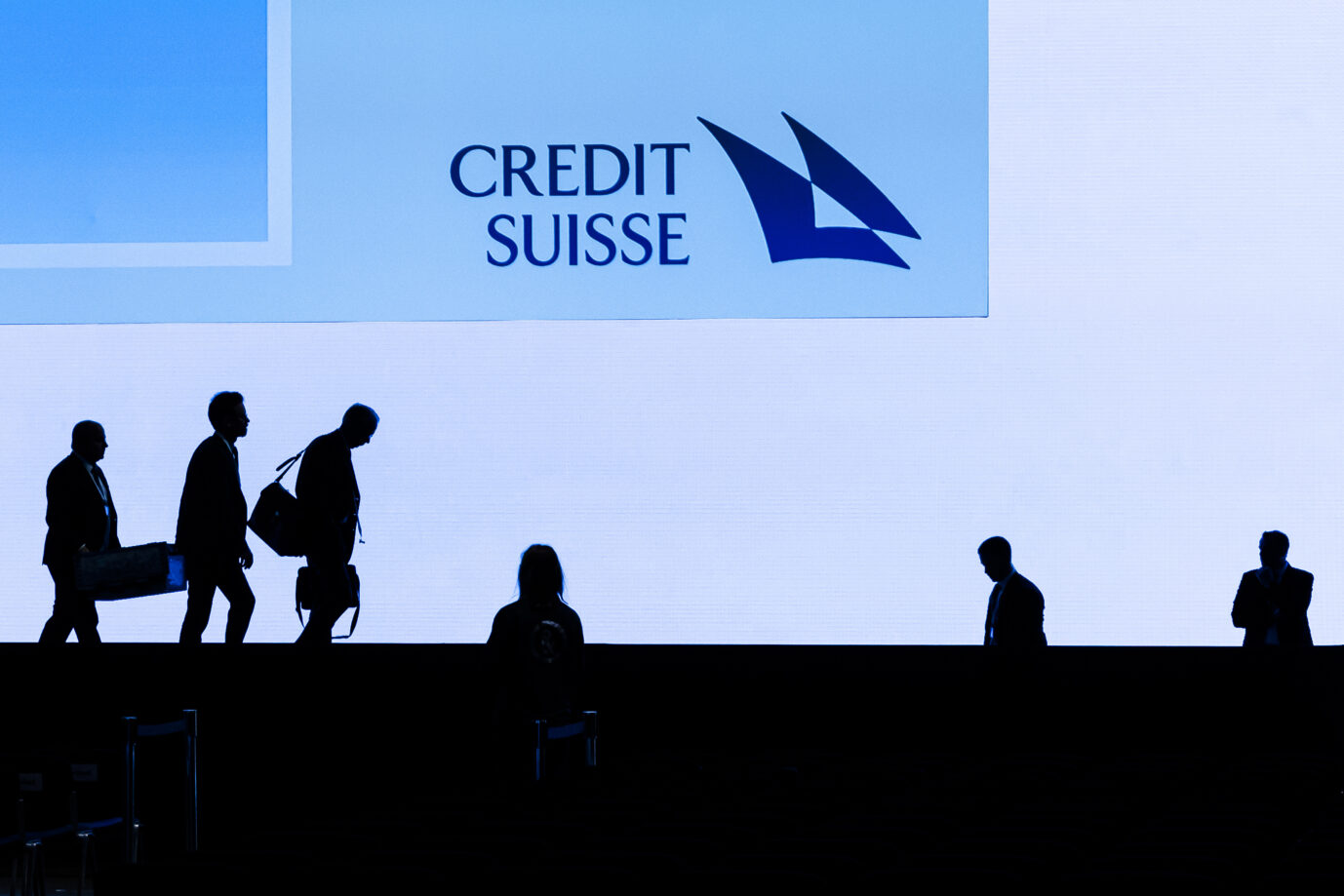 Das Bild zeigt Banker der Credtit Suisse-Bank vor dem Logo des Unternehmens.