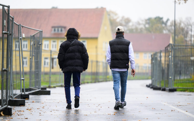 Zwei Migranten gehen über das Gelände eines Ankunftszentrums - laut Eurostat hat Deutschland zuletzt wieder zehntausende Asylbewerber aufgenommen Foto: picture alliance/dpa | Philipp Schulze