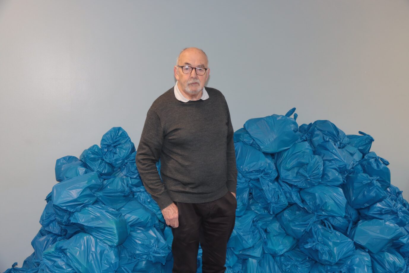 Der Leiter des Capuchin Day Centres in Dublin, der Hauptstadt von Irland, Alan Bailey, steht vor blauen Säcken mit Lebensmittelpaketen.