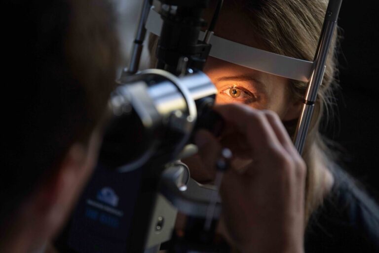 Ein Arzt untersucht das Auge einer Patientin nach einer Impfung.