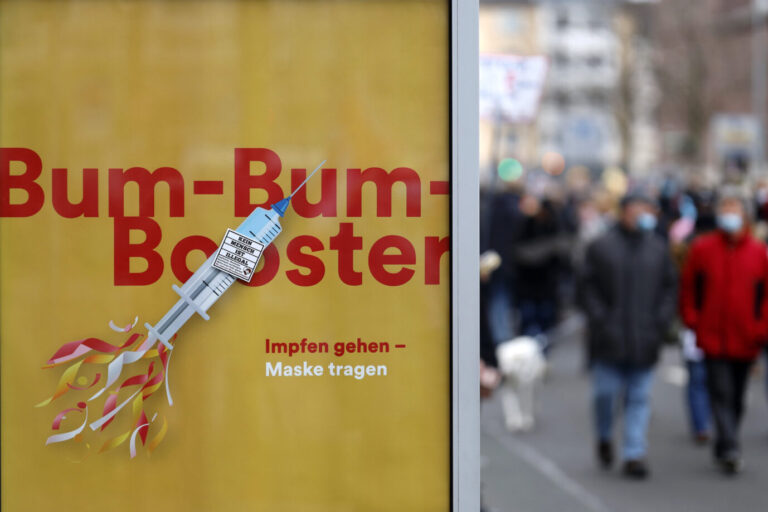 Eine Regierungswerbung der Stadt Düsseldorf am Rande der Demo empfiehlt mit 'Bum-Bum-Booster - Impfen gehen - Maske tragen' u.a. die Dreifachimpfung als Konzept für die Karnevalstage.
