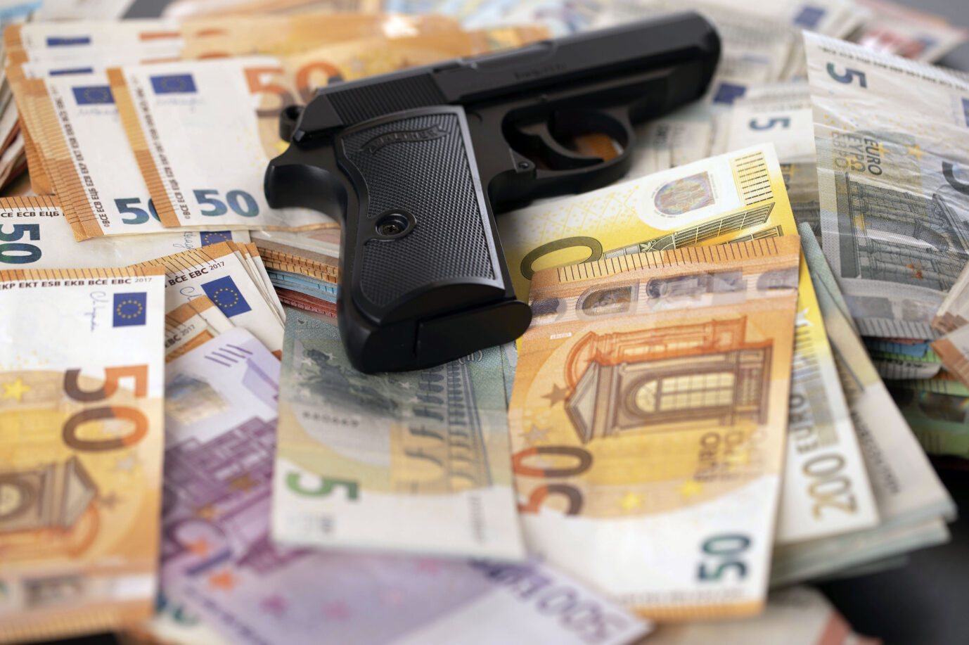 Ein Pistole auf geraubten Banknoten liegend. Die neue EU-Behörde Amla soll effektiver gegen Terrorfinanzierung und Geldwäsche vorgehen.(Symbolfoto, Themefoto)