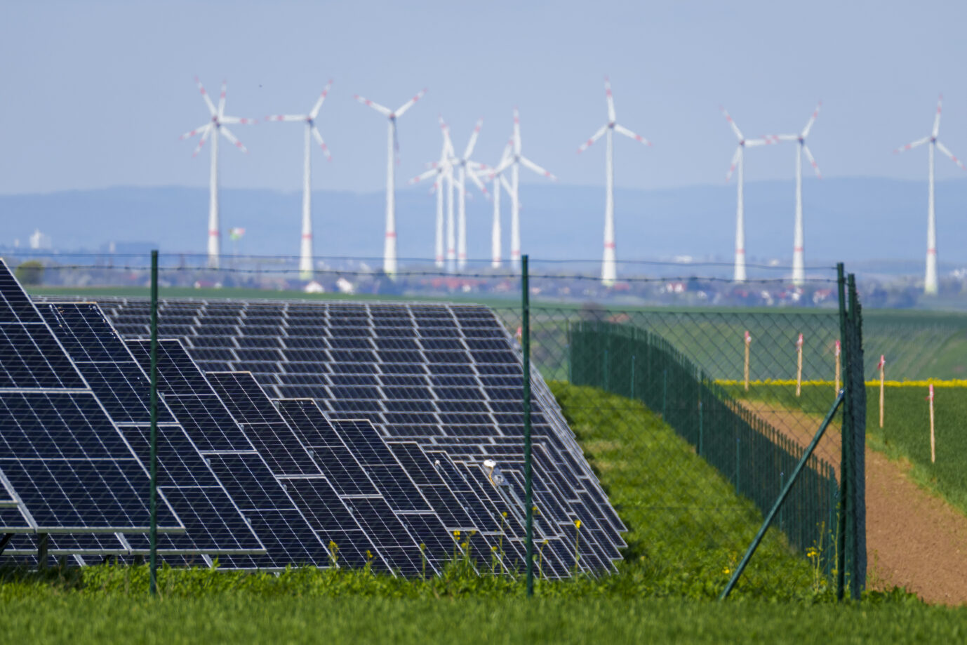 Ein Solarpark steht in unmittelbarer Nähe zu mehreren Windkraftanlagen, um die Klimawende zu vollbringen.