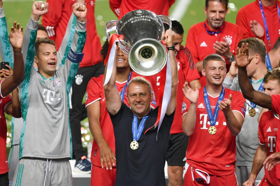 Das Foto zeigt Hansi Flick, der den Champions League Pokal in die Luft reckt.