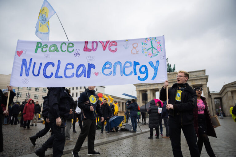 Teilnehmer eines Protests gegen die Abschaltung der letzten drei deutschen Kernkraftwerke des Vereins Nuklearia gehen mit einem Banner vor dem Brandenburger Tor, wo eine Aktion der Umweltorganisation Greenpeace stattfindet um die Abschaltung zu feiern. Das Thema Kernkraft wird in Deutschland kontrovers diskutiert.