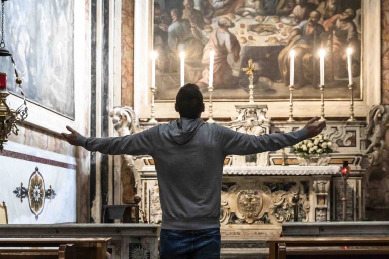 Ein junger Mann betet in seiner Religionsfreiheit in einer Kirche vor einem Altar.