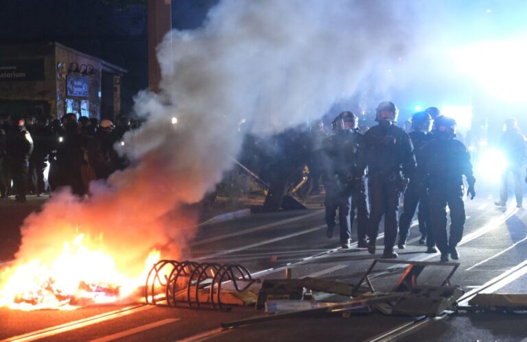 Polizisten gehen in Leipzig bei Ausschreitungen für Lina E. an einer brennenden Barrikade vorbei. Am Freitagabend randalierten Antifas im Stadtteil Connewitz.