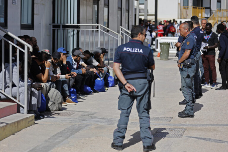 Polizisten bewachen die auf Lampedusa angekommenen Migranten.